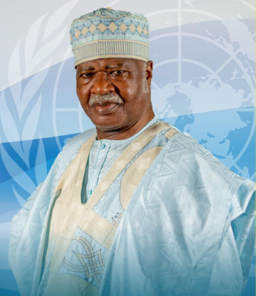 Man in traditional attire with UN backdrop.
